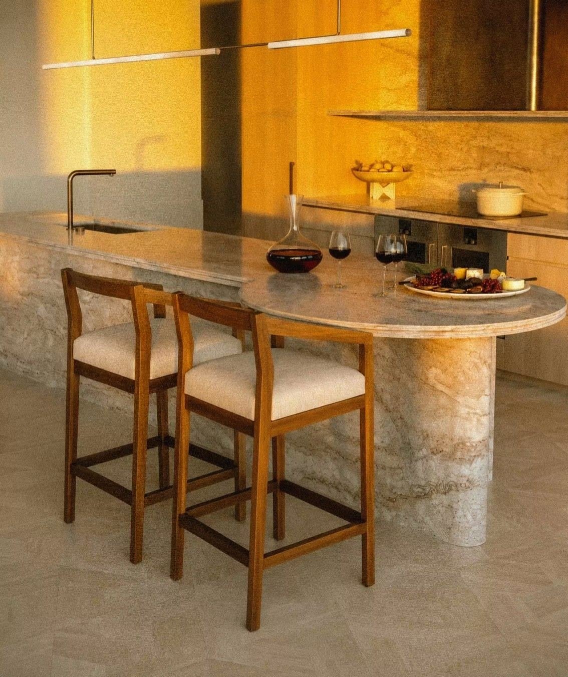 Isla de cocina en mármol con bancos de madera